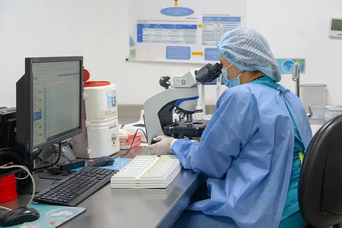 Mujer mirando a través de un microscopio en un laboratorio